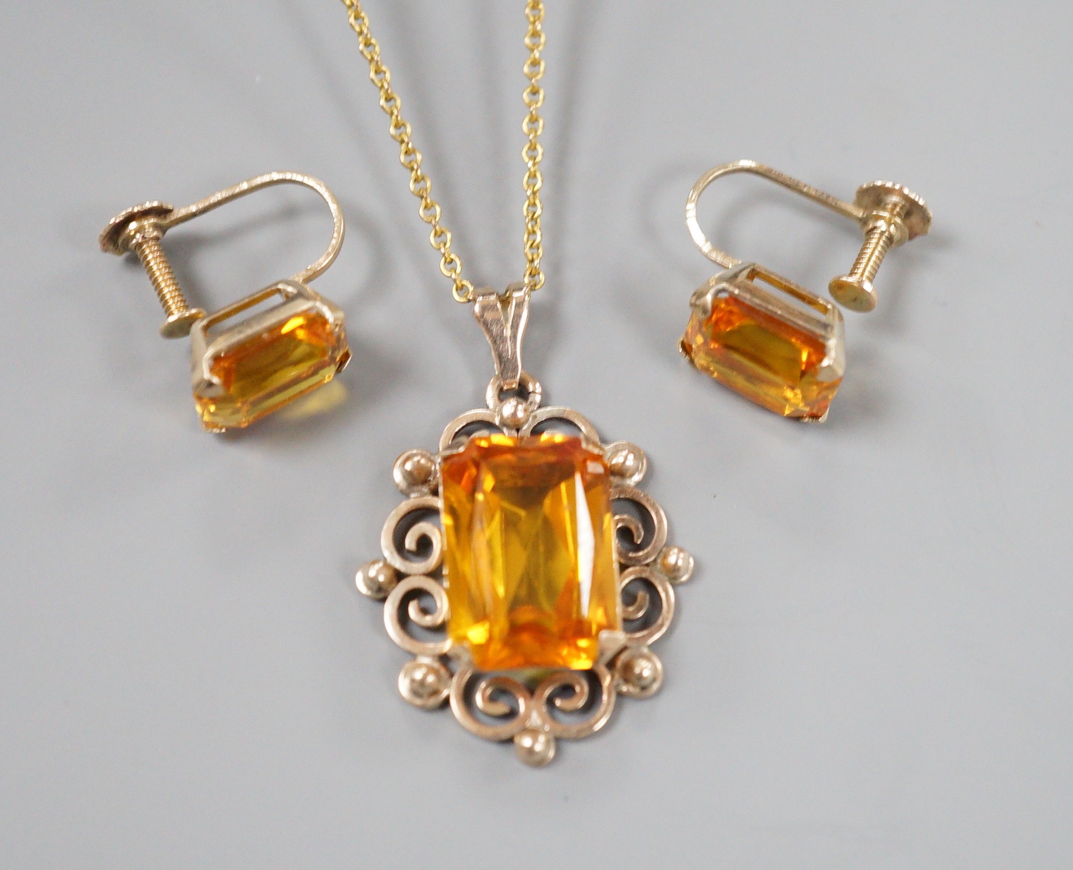 A yellow metal and citrine set pendant, 29mm, on a gold plated chain and a pair of 9ct and citrine set ear clips, gross 8.2 grams.
